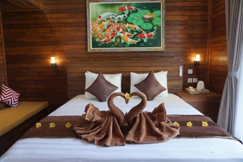 珀尼达岛辛嘎布度假村的两个毛巾天鹅坐在房间里的床边