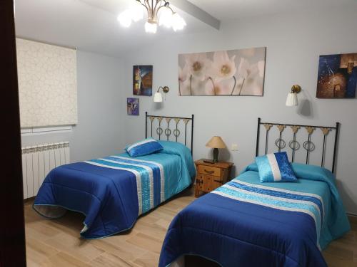 TraspinedoMaitemare的配有蓝色棉被的客房内的两张床