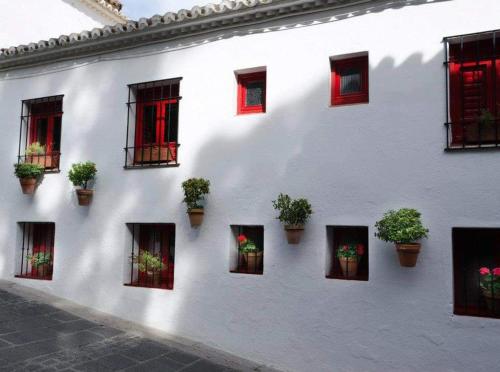 米哈斯科斯塔Valleverde Apartment的白色的建筑,有红色的窗户和盆栽植物