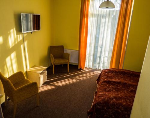 里加威玛加酒店的一间卧室配有一张床、一把椅子和电视。