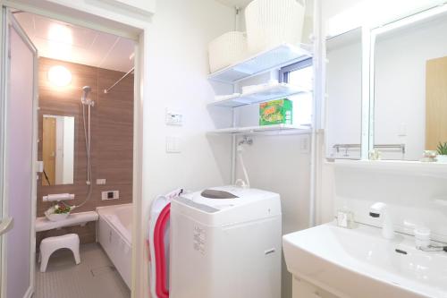 读谷村Bremen House ~ブレーメンハウス~的白色的浴室设有洗衣机和烘干机。