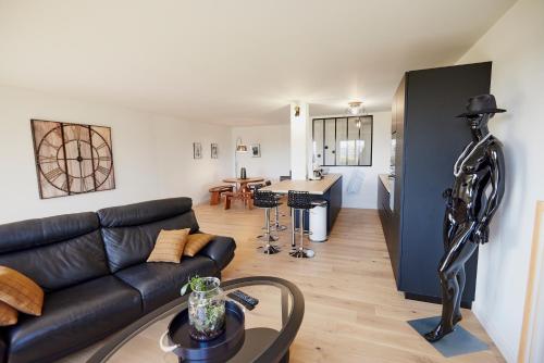 圣布里厄Jean Bart - proximité centre - 2 chambres 90 m2 avec jardin的一间带黑色沙发的客厅和一间厨房