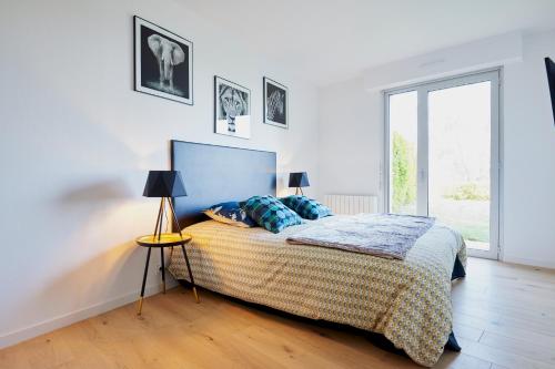 圣布里厄Jean Bart - proximité centre - 2 chambres 90 m2 avec jardin的一间卧室配有一张床、两盏灯和一个窗户。