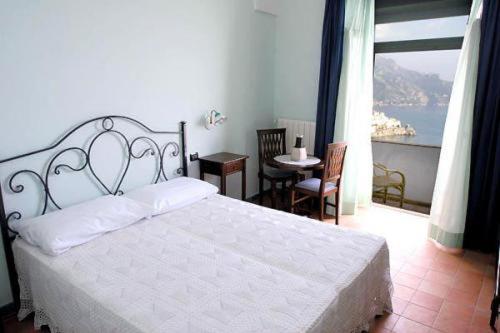 阿马尔菲瑞纳别墅式酒店的一间带一张白色大床的卧室和一个阳台