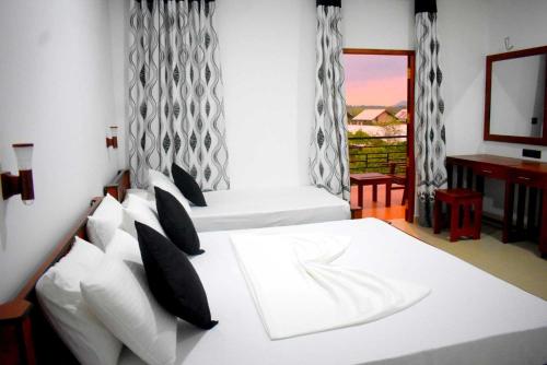 雅拉Blue Sky Hotel Yala的一间卧室设有两张床、一张桌子和一个窗口。