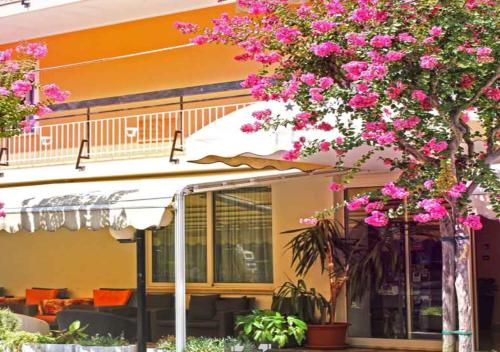 里米尼丽波特酒店的一座建筑物前有粉红色花的树