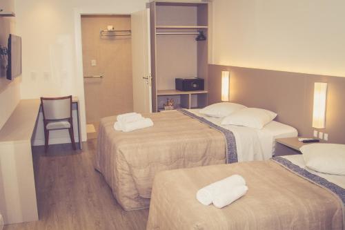 巴拉奈里奥-坎布里乌HOTEL LUAR ATLANTICO的酒店客房,设有三张床和椅子