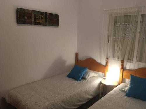 罗塔Casa Maria的一间卧室设有两张床、一盏灯和一扇窗户。
