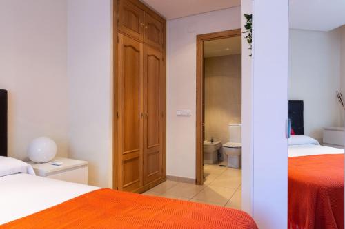马德里Apartamentos Duque的一间卧室设有两张床,一扇门通往浴室