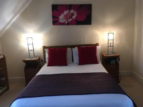 坎特伯雷Turi House的一间卧室配有一张带红色枕头的床和两盏灯。