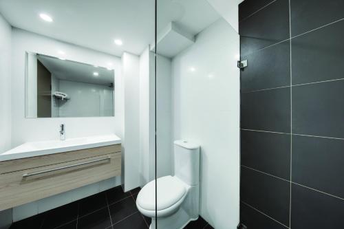 悉尼Central Studio Hotel Sydney的一间带卫生间、水槽和镜子的浴室