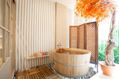 曼谷泰国柏龙日式旅馆的浴室设有木浴缸,里面有一棵树