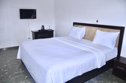 雅温得Hôtel La Couronne RW的一间卧室配有一张带白色床单的大床