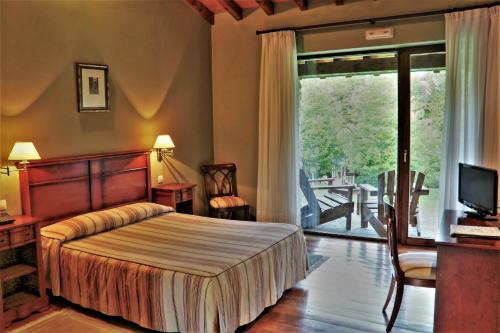 Toñanes拍拉兹恩德拖南尼斯酒店的一间卧室配有一张床、一台电视和一个阳台