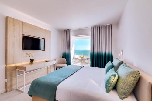 阿尔布费拉Hotel Sol e Mar Albufeira - Adults Only的配有一张床、一张书桌和一扇窗户的酒店客房