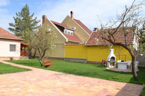 久洛Liliom Apartman的一座带黄色房子和砖砌车道的院子