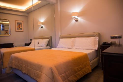 雅典马罗西酒店的酒店客房带两张带橙色床单的床