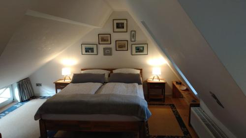 UtersumDas Rosenhaus的一间卧室配有一张带两盏灯的床,墙上挂有图片