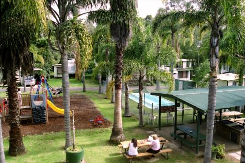 巴特曼斯贝Batemans Bay Holiday Park & Hostel的两人坐在公园的长椅上,公园里设有游乐场