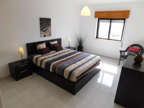 波尔蒂芒Tropical Rocha Residence的一间卧室设有床、两张桌子和一扇窗户