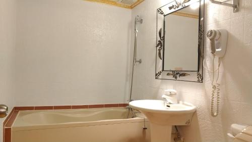 基隆阿乐哈大饭店的一间带水槽、浴缸和镜子的浴室