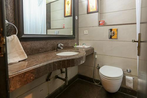 新德里The Oakland Plaza by Orion Hotels的一间带卫生间、水槽和镜子的浴室