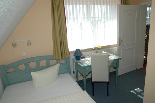 瓦尔内明德Landhotel Ostseetraum & Fewo的一间卧室配有一张床、一张桌子和一个窗户。