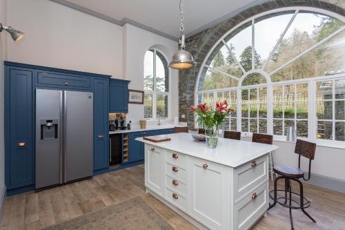 安布尔塞德The Lake House, Wansfell Holme, Windermere的厨房配有蓝色和白色的橱柜和大窗户