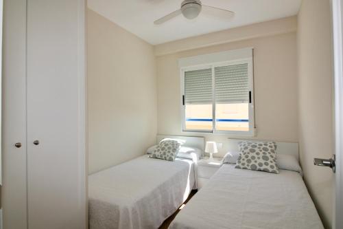 奥利瓦Apartamento con piscina y vistas al mar Aguamarina 36的一间小卧室,配有两张床和窗户