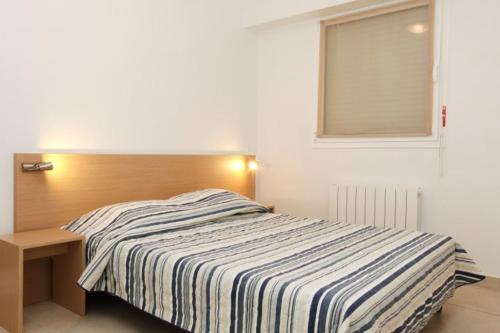 阿卡雄VVF Résidence Arcachon的一间卧室配有一张带木制床头板的床和窗户。