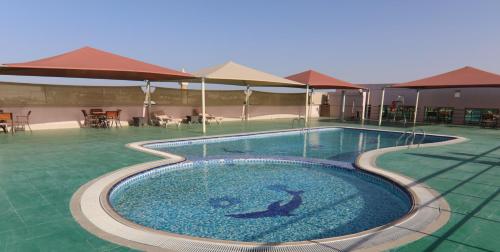 艾恩All Seasons Hotel Al Ain - Previously City Seasons的度假村内的大型游泳池,配有桌子和遮阳伞