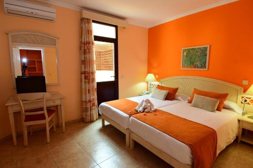 莫罗德哈布雷Villamar Hotel的一间卧室设有橙色的墙壁、一张床和一张书桌