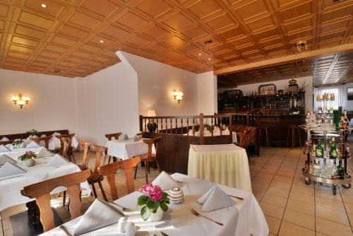 IchtershausenLandgasthof & Hotel KRONE Eischleben的餐厅设有白色的桌子和木制天花板。