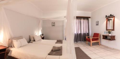 马尔塔赫厄Maltahöhe Hotel的白色卧室,配有床和红色椅子