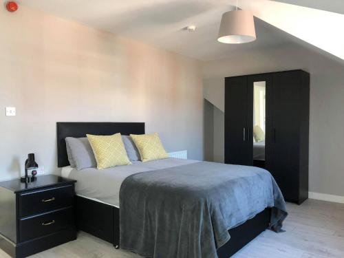 贝尔法斯特Wellesley Avenue的一间卧室配有一张带黑色床头板和黄色枕头的床。