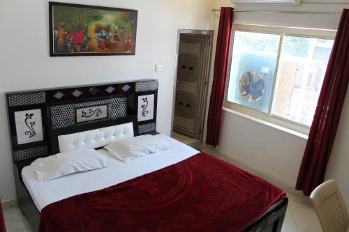 奥拉奇哈Best B&B in Orchha的一间卧室配有一张带红色毯子的床和窗户。