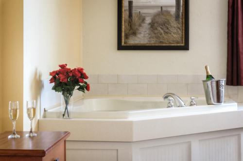 西雅茅斯碧沙度假酒店的浴室设有白色浴缸,并配以红花花瓶