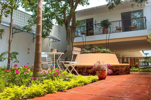 蒙波斯La Gloria Hotel by BespokeColombia的一座建筑前带长凳和鲜花的庭院