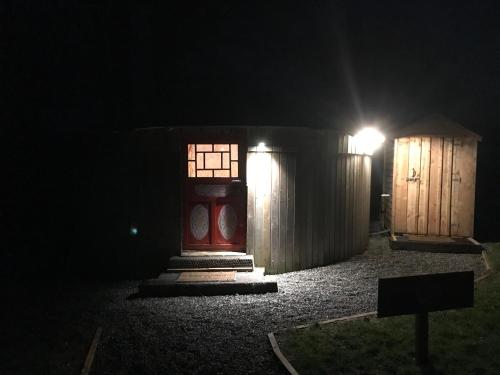 基尔肯尼McClure Yurt at Carrigeen Glamping的红色的门和晚上的木制棚子