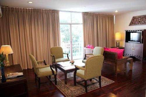曼谷山森套房/两卧室套房公寓的客厅配有桌椅和电视