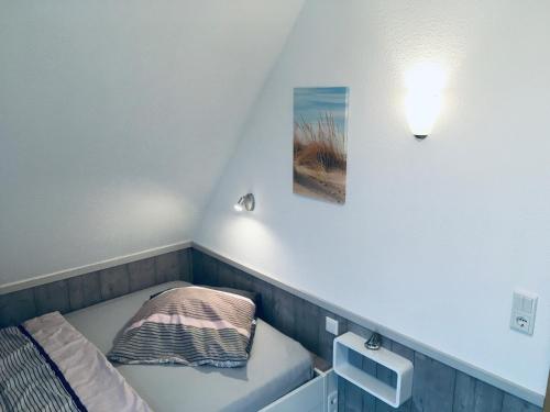 文尼斯塔特Ferienhaus Holst Sylt的小房间,配有一张床,墙上挂着一张照片
