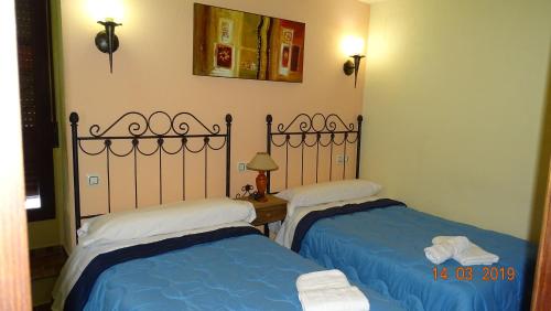 HinojaresCasa Rural La Liebre的配有两张蓝色和白色床单的床铺