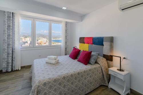 托雷德尔马尔ÁTICO CON VISTAS ESPECTACULARES AL MAR的一间卧室配有一张带色彩缤纷枕头的床和窗户。
