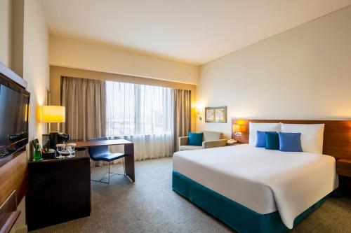迪拜Novotel Deira Creekside Dubai的酒店客房设有一张大床和一台电视。