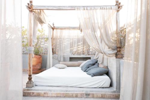 马拉喀什里亚德乐瑞哈尼酒店的卧室内的天蓬床和白色窗帘