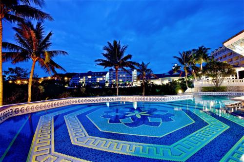 盐寮远雄悦来大饭店的棕榈树和建筑的夜间游泳池
