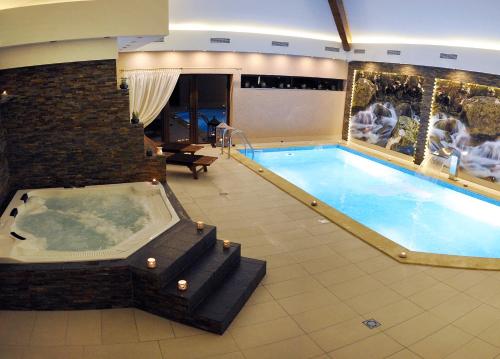 亚诺托维克Hotel Dębowe Wzgórze Wellness & Spa - zarezerwuj w maju 2 noclegi a wypożyczenie rowerów będzie GRATIS!的一个带热水浴缸的大型室内游泳池