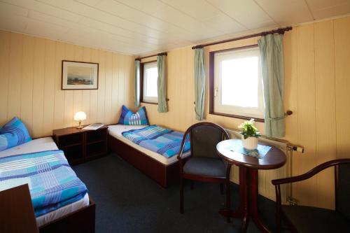欧巴德伍斯图Hotelschiff Stinne的一间设有两张床、一张桌子和一把椅子的房间