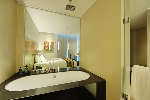 雅加达Ra Premiere Simatupang Jakarta的一间带浴缸的浴室和一张位于客房内的床