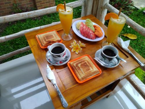 珀尼达岛Angels Bungalow Nusa Penida的一张桌子,上面有早餐食品和两杯橙汁
